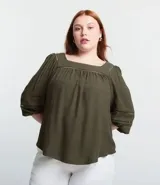 Blusa verde militar de viscosa con escote cuadrado y mangas 3/4 abullonadas con elásticos en los puños. Dispone de inserciones en el escote y en las mangas.