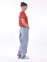 Remera roja de manga corta, corte cropped y cuello redondo con ribete a rayas blancas y doradas.