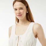Blusa blanca sin mangas con bordado inglés, escote en V y lazos ajustables en el frente.