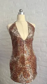 Vestido corto con estampado animal print en tonos marrones y blancos, con escote halter pronunciado y espalda descubierta.