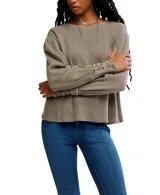 Buzo blanco de algodón con escote a la base, hombros caídos y mangas amplias con detalle de ojalillos y cordones en los puños.