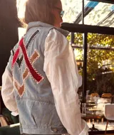 Chaleco de jean celeste con apliques geométricos en terciopelo rojo y negro, formados y bordados a mano.