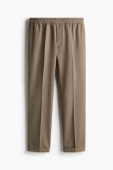 Pantalón de vestir color beige, de corte slim fit, con cintura elástica y cordón ajustable.