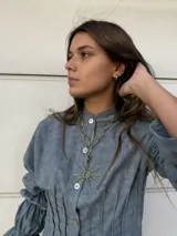 Collar con cadena de eslabones dorados y dije en forma de sol con rayos.