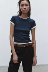 Pantalón negro de tiro alto con pernera recta, bolsillos frontales y falsos bolsillos con solapa en la espalda. Incluye cinturón marrón de cuero sintético.