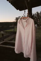 Camisa oversize color rosa claro a rayas verticales blancas, con cuello mao y mangas largas con puños elásticos.