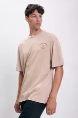 Remera color visón de corte amplio con estampa pequeña en el pecho.