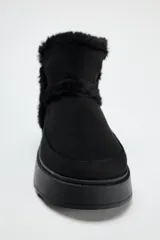 Botín negro de caña baja con interior de efecto pelo y suela tipo flatforma.