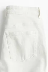 Jean tobillero de cinco bolsillos en denim blanco levemente elástico. Modelo de tiro superalto con cierre y piernas levemente ajustadas en el bajo.
