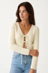 Top manga larga color crema, de punto crochet, con escote en V y cierre frontal con lazos.