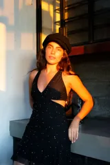 Vestido corto negro con estampado de hojas doradas, escote en V, breteles finos cruzados en la espalda, cut-outs laterales bajo el busto y volado en el ruedo.