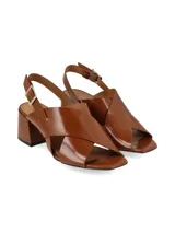 Sandalias negras de charol con tiras cruzadas, tacón cuadrado y pulsera al tobillo con hebilla metálica.