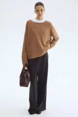 Buzo de punto fino color camel, de corte holgado con escote redondo y mangas raglán. Presenta cuello, puños y bajo acanalados.