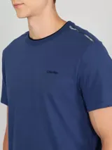 Remera azul de manga corta con cuello redondo y logo de Calvin Klein bordado en el pecho. Presenta una cinta distintiva en los hombros.