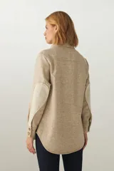 Camisa estilo leñador color beige con textura de espiga, de manga larga con puños abotonados, cuello clásico, cierre frontal con botones y dos bolsillos de parche con solapa abotonada en el pecho.