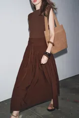 Vestido midi marrón con cuello barco y manga sisa. Presenta un corte a la altura de la cintura con detalle de trabilla y lazo del mismo tejido. Cierre lateral con cremallera oculta.