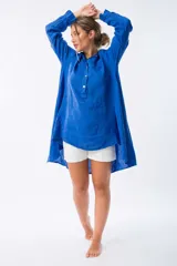 Camisa azul de lino con botones de nácar, corte amplio y largo irregular.