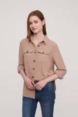 Camisa de color marfil con botones frontales y bolsillos en el pecho, de manga larga y tejido ligero.