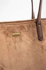 Bolso tipo tote de gamuza vegana color camel, con asas de mano y logo grabado en el frente.