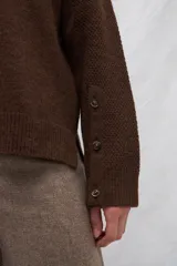 Cárdigan marrón de tejido de punto industrial con escote en V, combinación de puntos y botones en las mangas.