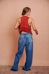 Pantalón de jean celeste de corte recto, con detalles de apliques desflecados en los bolsillos delanteros y roturas en la pierna.