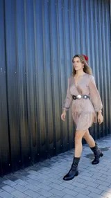 Vestido corto color marrón claro con hilos plateados, escote en V cruzado y mangas largas abullonadas.