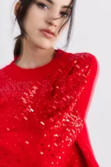 Sweater rojo de tejido de punto con cuello redondo y mangas largas. Diseño con lentejuelas bordadas en el frente y las mangas.