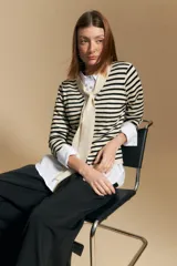 Cárdigan de tejido de punto a rayas horizontales anchas, color crema y negro. Presenta un cuello tipo chal que se anuda al frente como un lazo.