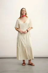 Vestido midi color beige con textura, escote en V, mangas cortas y abotonadura frontal.