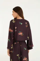 Blusa corta color marrón con estampado de cócteles, escote en V con lazo, mangas largas acampanadas y corte holgado.