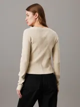 Cárdigan color crema de punto de algodón suave con textura de canalé, corte slim, cuello en V, manga larga, cierre de botones e insignia tonal de Calvin Klein en el bajo.