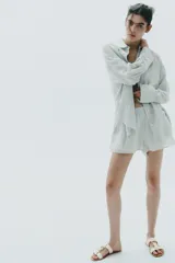 Sandalia plana color crema con doble tira y hebilla metálica dorada.