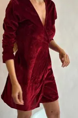 Vestido corto de terciopelo azul marino, con escote cruzado en V, mangas largas y lazo lateral ajustable.