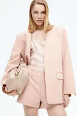 Short de vestir color rosa pálido, de corte recto, con bolsillos laterales y traseros. Se ajusta a la cintura con botón y cierre oculto.