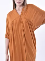 Vestido color naranja, corte irregular, con cuello en V y botones frontales.