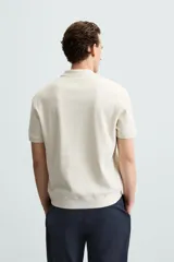 Polo azul marino de punto con textura acanalada vertical, corte regular fit, cuello solapa con abertura frontal y mangas cortas.