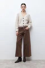 Cardigan de tejido de punto color beige melange, con escote en V, manga larga abullonada y cierre frontal con botones oscuros.