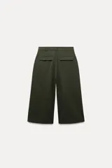 Bermuda larga color verde oscuro de tiro medio y pierna ancha. Confeccionada en hilatura con 19% de lana. Presenta trabillas en la cintura, bolsillos laterales y con solapa en la espalda, pinzas en el delantero y cierre frontal con cremallera y botones.