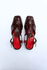 Sandalias de cuero color borgoña con textura croco, diseño cerrado en la parte delantera con aberturas laterales, punta cuadrada y cierre con hebilla ajustable en el tobillo. Taco ancho de 3 cm.