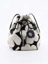 Bolso bandolera tipo bucket con estampado de flores en blanco y negro, con ajuste superior de cordón y correa larga de hombro negra.