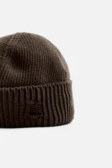 Gorro de lana tejido en punto morado oscuro, con vuelta y detalles rotos.