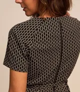 Vestido corto negro con estampado geométrico en color crema, de corte recto, manga corta y cuello redondo. Incluye cinturón fino del mismo tejido.