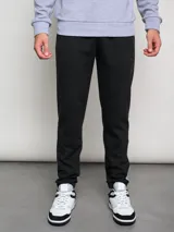 Pantalón de jogging negro con puños ajustados, cortes laterales y cambio de color en la parte inferior de la pierna.