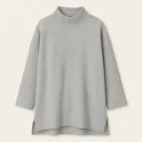 Sweater negro de tejido texturizado, con cuello alto, mangas 3/4 y corte asimétrico con aberturas laterales.