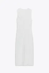 Vestido midi blanco con estampado de cuadros grises, cuello redondo y sin mangas. Presenta detalle drapeado en el frente y cierre oculto en la espalda.