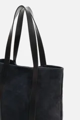 Bolso tipo shopper fabricado en piel de alta calidad con acabado serraje color negro. Tiene compartimento principal con cierre de imán, bolsillo interior con cremallera y asas de mano de piel.