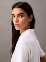 Remera corta de algodón blanco con textura acanalada, cuello polo con abertura y logo CK bordado en el pecho.