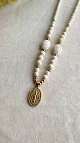 Collar de piedra reconstituida blanca con dije de virgen milagrosa dorada en acero quirúrgico.
