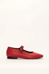 Zapato plano estilo Mary Jane de cuero rojo, con punta fina y tira ajustable con hebilla negra sobre el empeine.