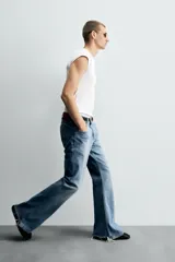 Pantalón de jean celeste, de tiro medio, corte ajustado en la parte superior y acampanado desde la rodilla. Tiene cinco bolsillos, efecto lavado y bajo irregular.